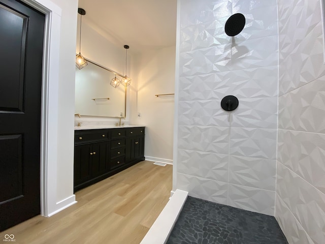 bathroom featuring hardwood / wood-style floors, vanity, and tiled shower