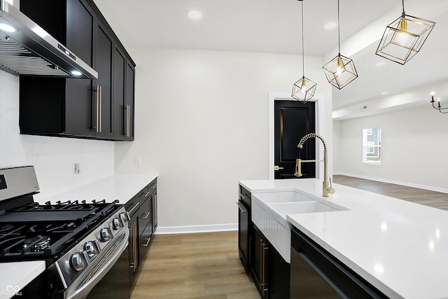 kitchen featuring hardwood / wood-style floors, sink, hanging light fixtures, wall chimney exhaust hood, and stainless steel appliances