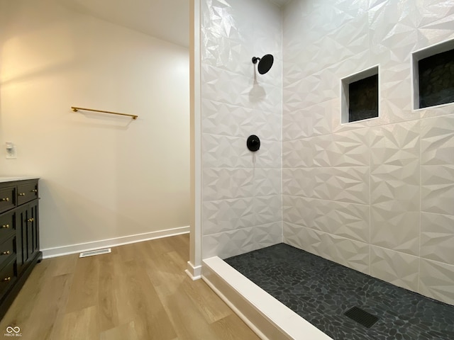 bathroom featuring tiled shower, hardwood / wood-style floors, and vanity