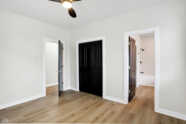 unfurnished bedroom with a closet, light wood-type flooring, ensuite bathroom, and ceiling fan