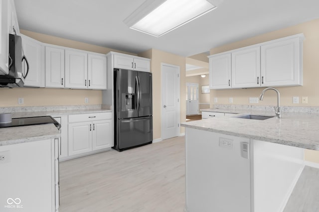 kitchen with stainless steel fridge, light hardwood / wood-style floors, white cabinetry, and sink