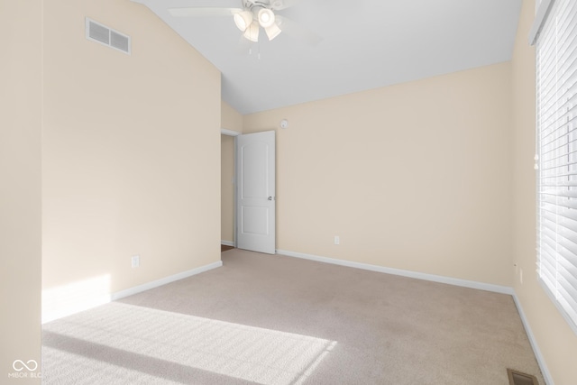 empty room with ceiling fan, lofted ceiling, light carpet, and a wealth of natural light