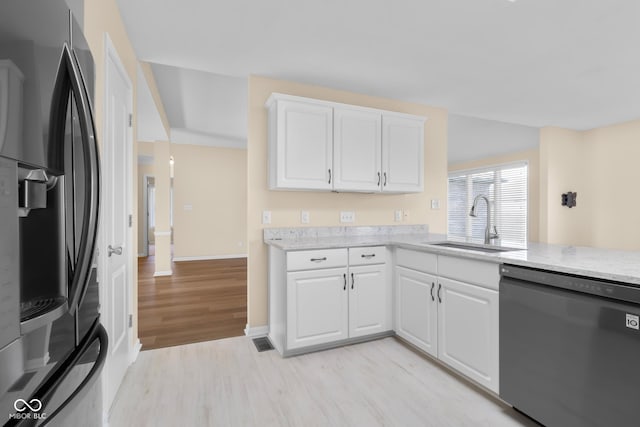 kitchen featuring white cabinets, stainless steel fridge, light wood-type flooring, and black dishwasher