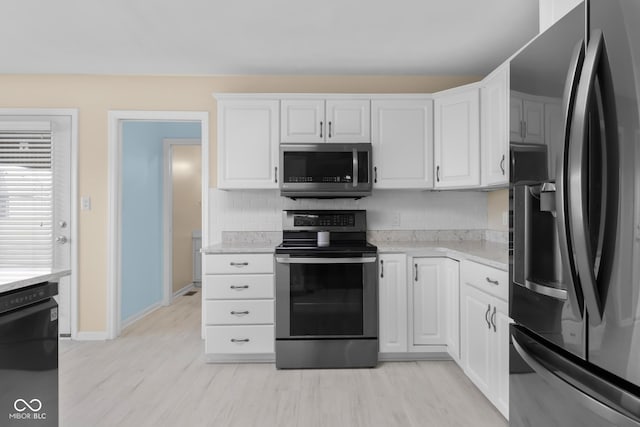 kitchen with appliances with stainless steel finishes, tasteful backsplash, white cabinetry, and light stone counters