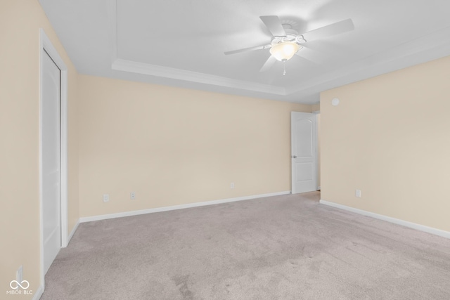 unfurnished room with light carpet, a tray ceiling, and ceiling fan