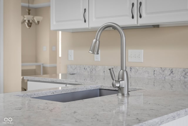 room details with light stone counters, sink, and white cabinets