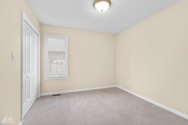 unfurnished bedroom featuring light colored carpet and a closet