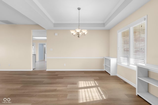 empty room with plenty of natural light, a chandelier, and hardwood / wood-style flooring