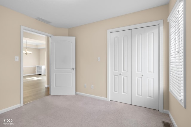 unfurnished bedroom featuring a chandelier, light colored carpet, and a closet