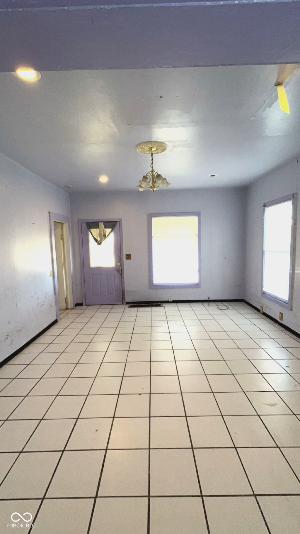 tiled spare room with an inviting chandelier