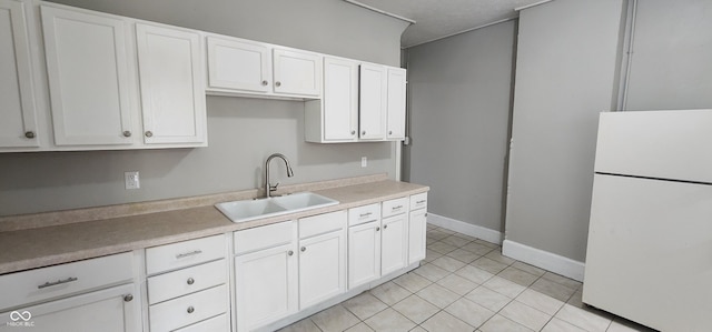 kitchen with white cabinets, sink, white fridge, and light tile patterned floors