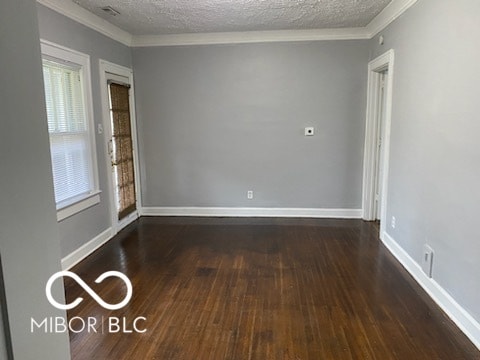 unfurnished room featuring dark wood-type flooring, a textured ceiling, and ornamental molding