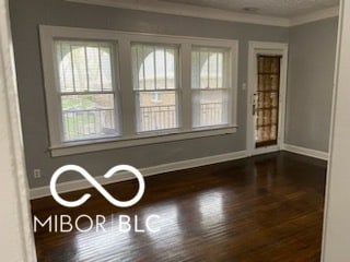 empty room featuring dark hardwood / wood-style flooring and crown molding