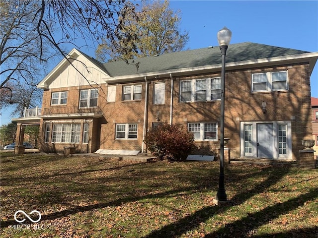 rear view of property featuring a yard and a balcony