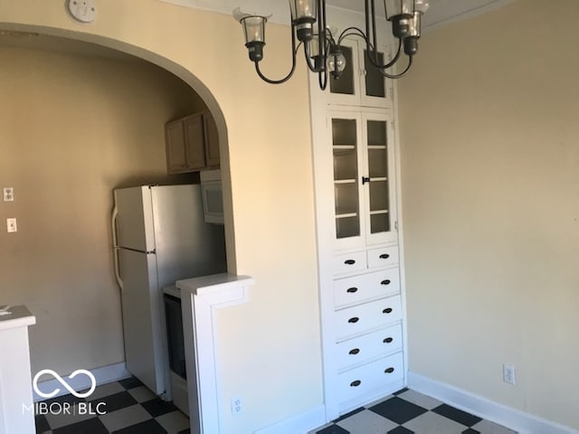 kitchen featuring a chandelier, white fridge, and white cabinetry