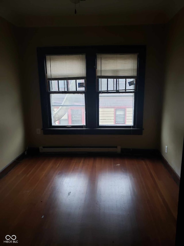 spare room featuring dark hardwood / wood-style flooring, a baseboard radiator, and ceiling fan