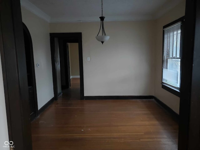 unfurnished dining area with crown molding and dark wood-type flooring