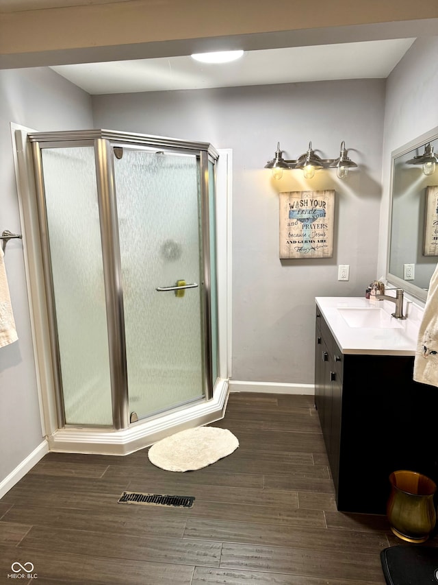 bathroom with hardwood / wood-style floors, vanity, and a shower with door