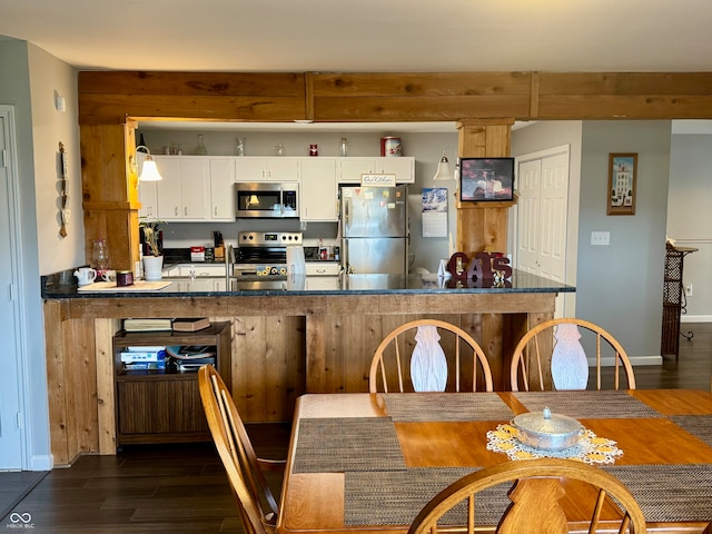 kitchen featuring kitchen peninsula, dark hardwood / wood-style flooring, stainless steel appliances, and white cabinets