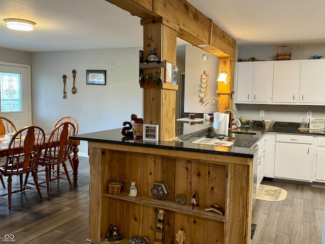 kitchen featuring kitchen peninsula, white cabinetry, sink, and dark wood-type flooring