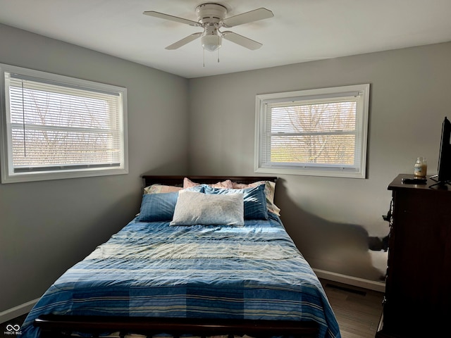 bedroom with multiple windows, ceiling fan, and hardwood / wood-style floors