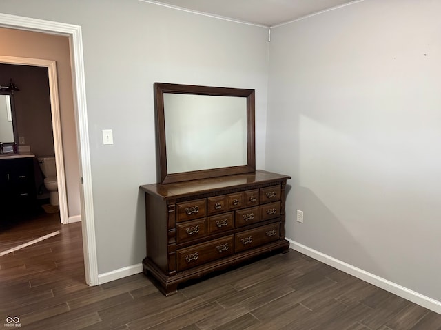 bedroom with ensuite bath and dark wood-type flooring