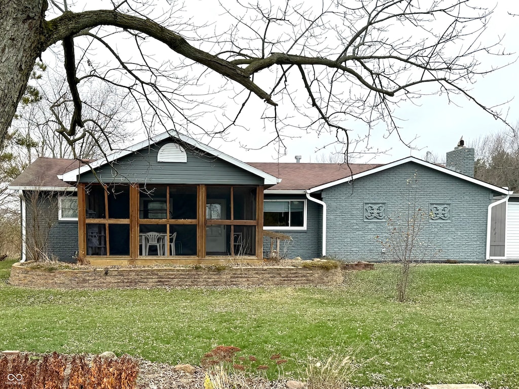 rear view of property with a lawn and a sunroom