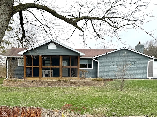 rear view of property with a lawn and a sunroom