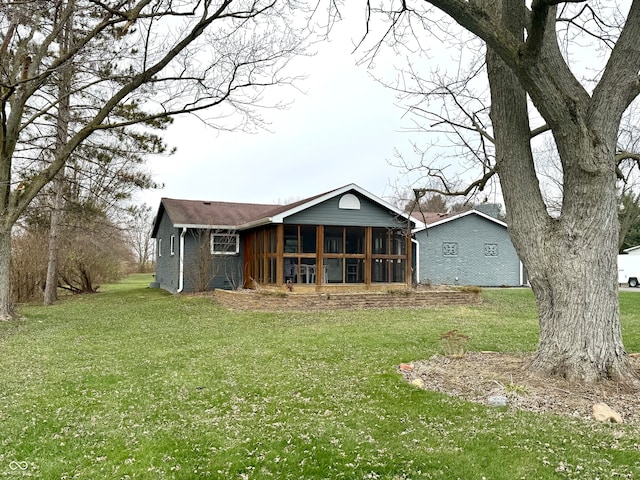 rear view of house featuring a yard and a sunroom