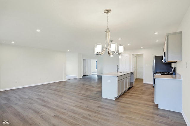 kitchen with sink, hanging light fixtures, gray cabinets, and a kitchen island with sink