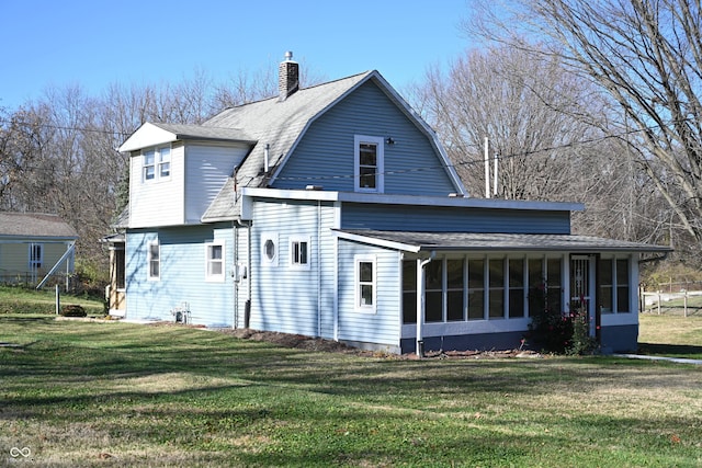 back of property with a sunroom and a yard