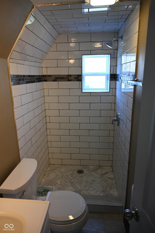 bathroom with vanity, toilet, and tiled shower