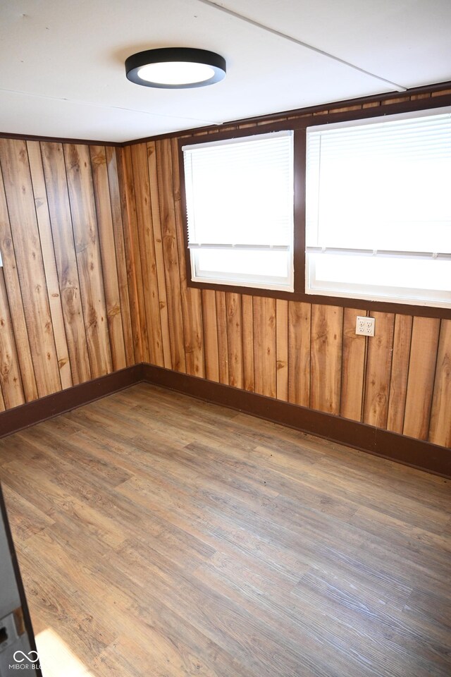 empty room featuring hardwood / wood-style flooring and wooden walls