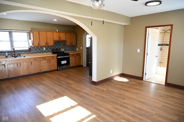 kitchen with backsplash, stainless steel range, dark hardwood / wood-style floors, and sink