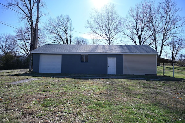 view of outdoor structure with a lawn, a garage, and a carport