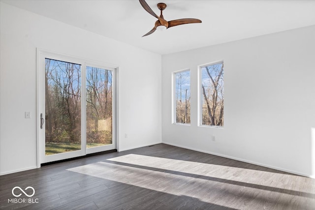 unfurnished room featuring ceiling fan, plenty of natural light, and dark wood-type flooring