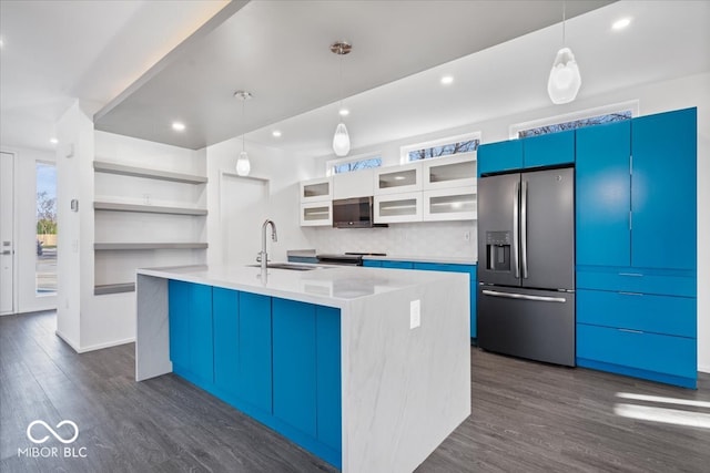 kitchen with dark hardwood / wood-style flooring, stainless steel appliances, sink, decorative light fixtures, and an island with sink