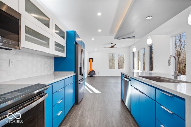 kitchen featuring dark wood-type flooring, blue cabinets, sink, ceiling fan, and stainless steel appliances