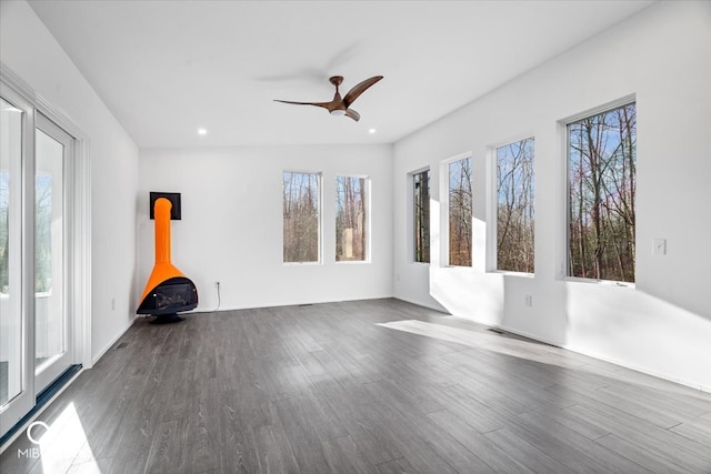 spare room with a wood stove, dark hardwood / wood-style flooring, and a healthy amount of sunlight