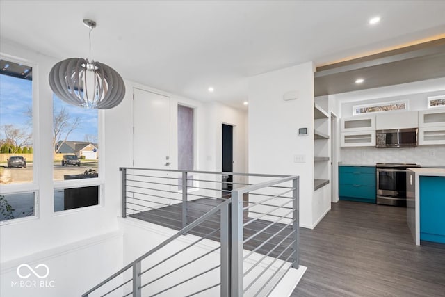 kitchen with hanging light fixtures, an inviting chandelier, dark hardwood / wood-style flooring, backsplash, and appliances with stainless steel finishes