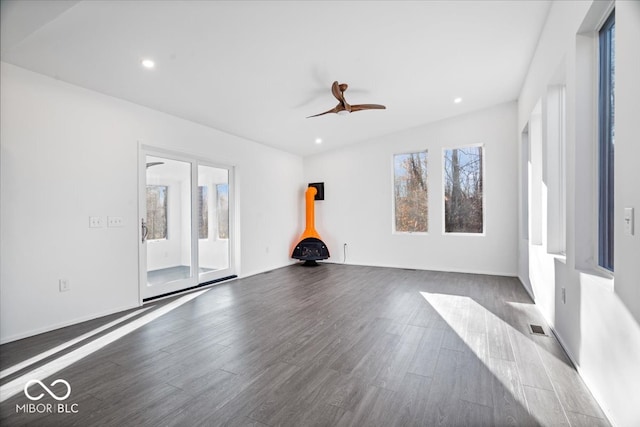 interior space with dark hardwood / wood-style floors, a wood stove, and ceiling fan