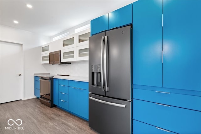 kitchen with backsplash, blue cabinets, stainless steel appliances, and hardwood / wood-style flooring