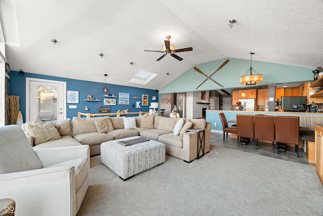 carpeted living room with ceiling fan with notable chandelier and lofted ceiling with skylight