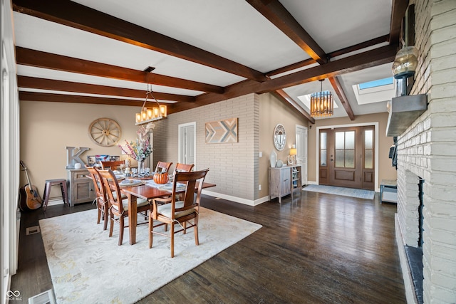 dining room with vaulted ceiling with skylight, dark hardwood / wood-style floors, a fireplace, and a notable chandelier