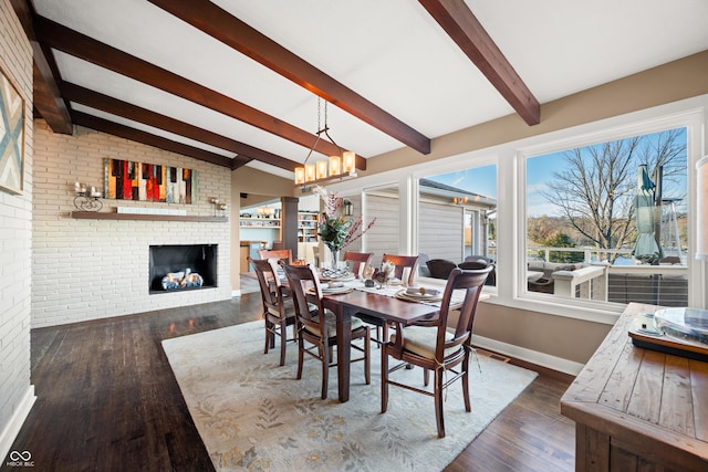 dining area featuring lofted ceiling with beams, dark hardwood / wood-style flooring, brick wall, and a brick fireplace