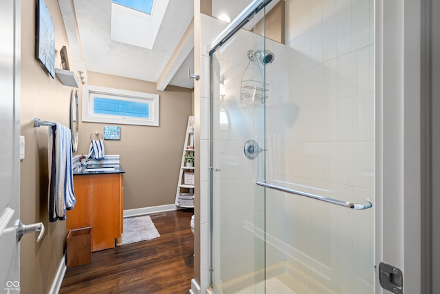 bathroom with a skylight, hardwood / wood-style flooring, and an enclosed shower