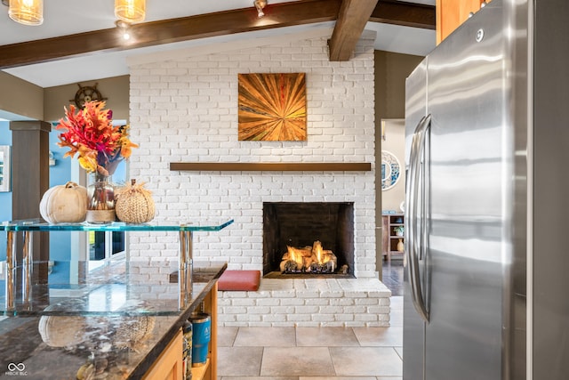 kitchen featuring lofted ceiling with beams, stainless steel fridge, light tile patterned floors, and a fireplace