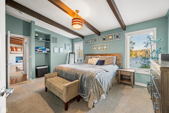 bedroom with ceiling fan, beamed ceiling, and light colored carpet