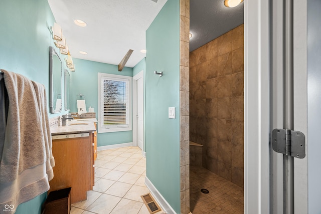 bathroom with a tile shower, vanity, a textured ceiling, and tile patterned floors