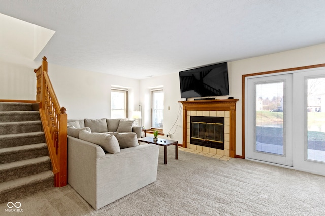 living room with a textured ceiling, light carpet, and a tile fireplace